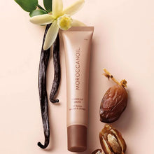 Load image into Gallery viewer, Moroccanoil lip balm with vanilla bean, date, and flower on a light pink background